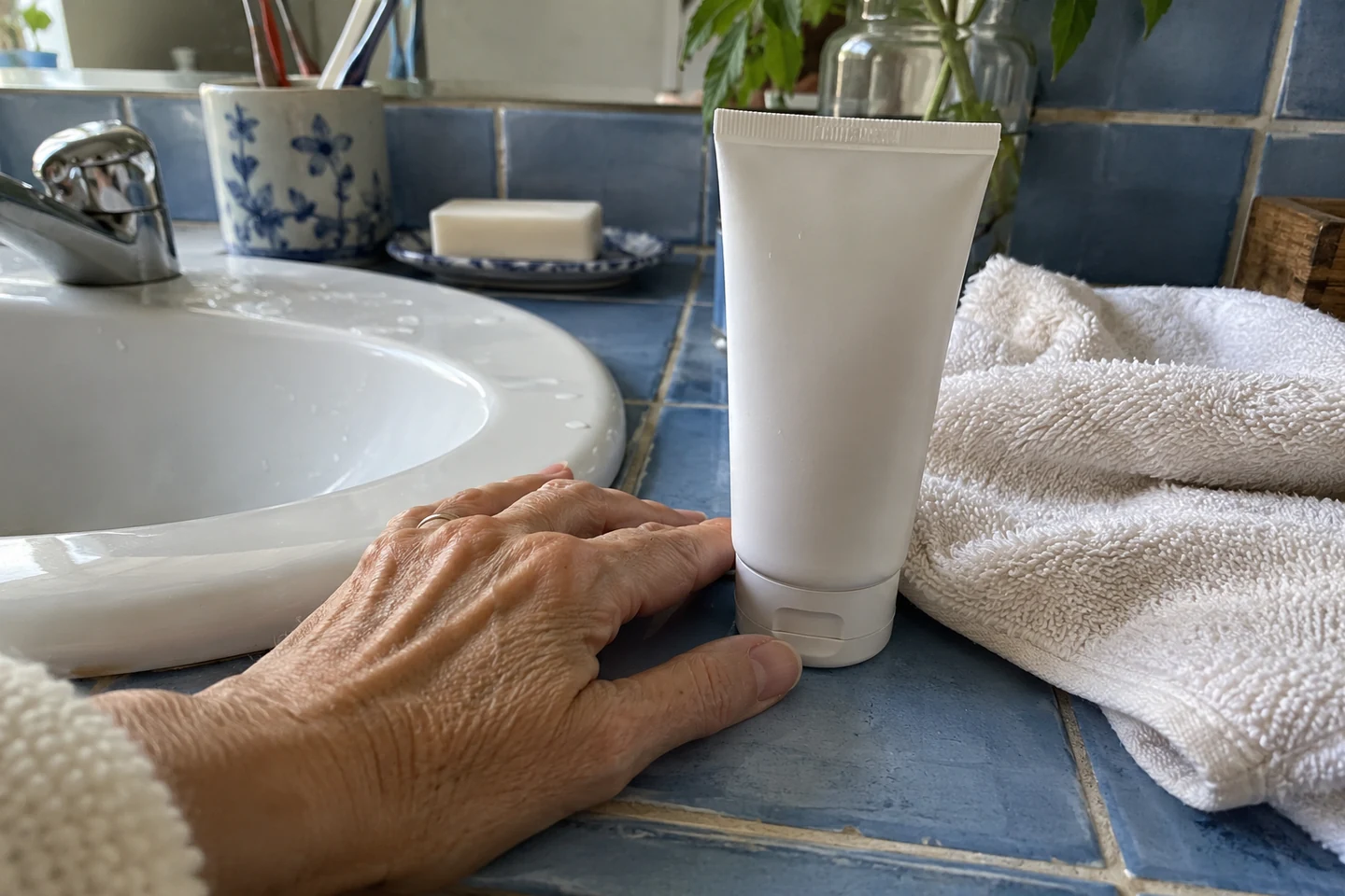 Un tube de crème et une serviette douce près d’un lavabo