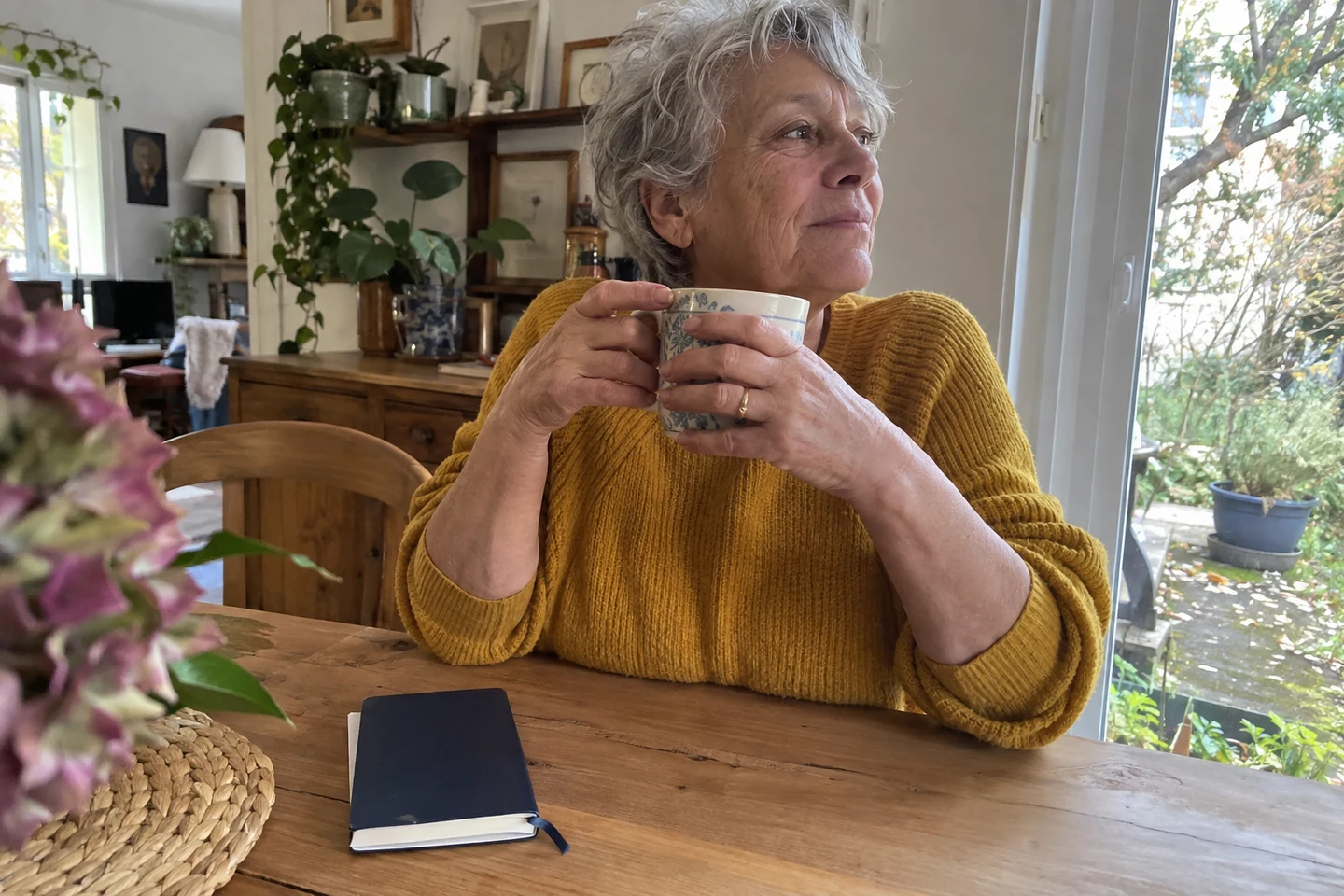 Une femme fait une pause avec une tasse près de la fenêtre