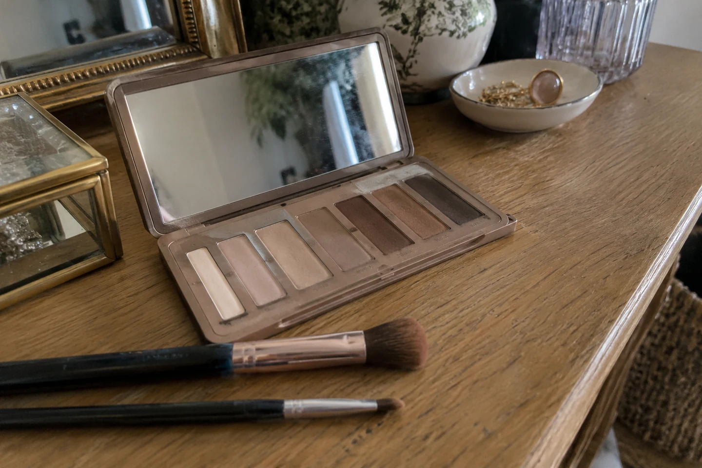 Une palette de fards neutres et des pinceaux sur une coiffeuse