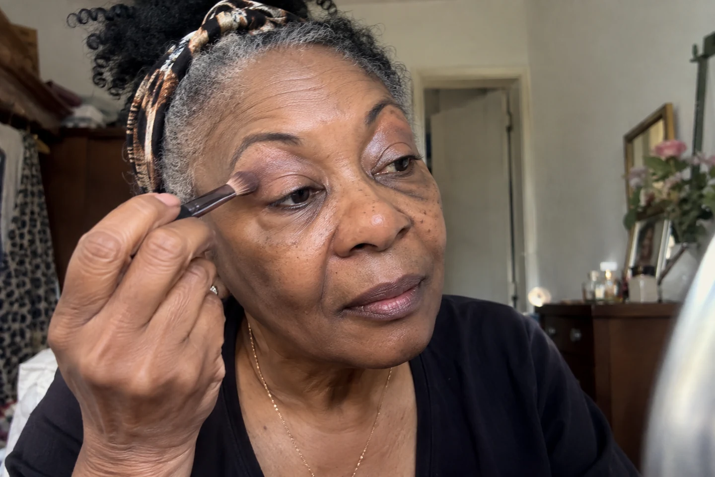 Une femme pose un fard clair sur sa paupière avec un pinceau