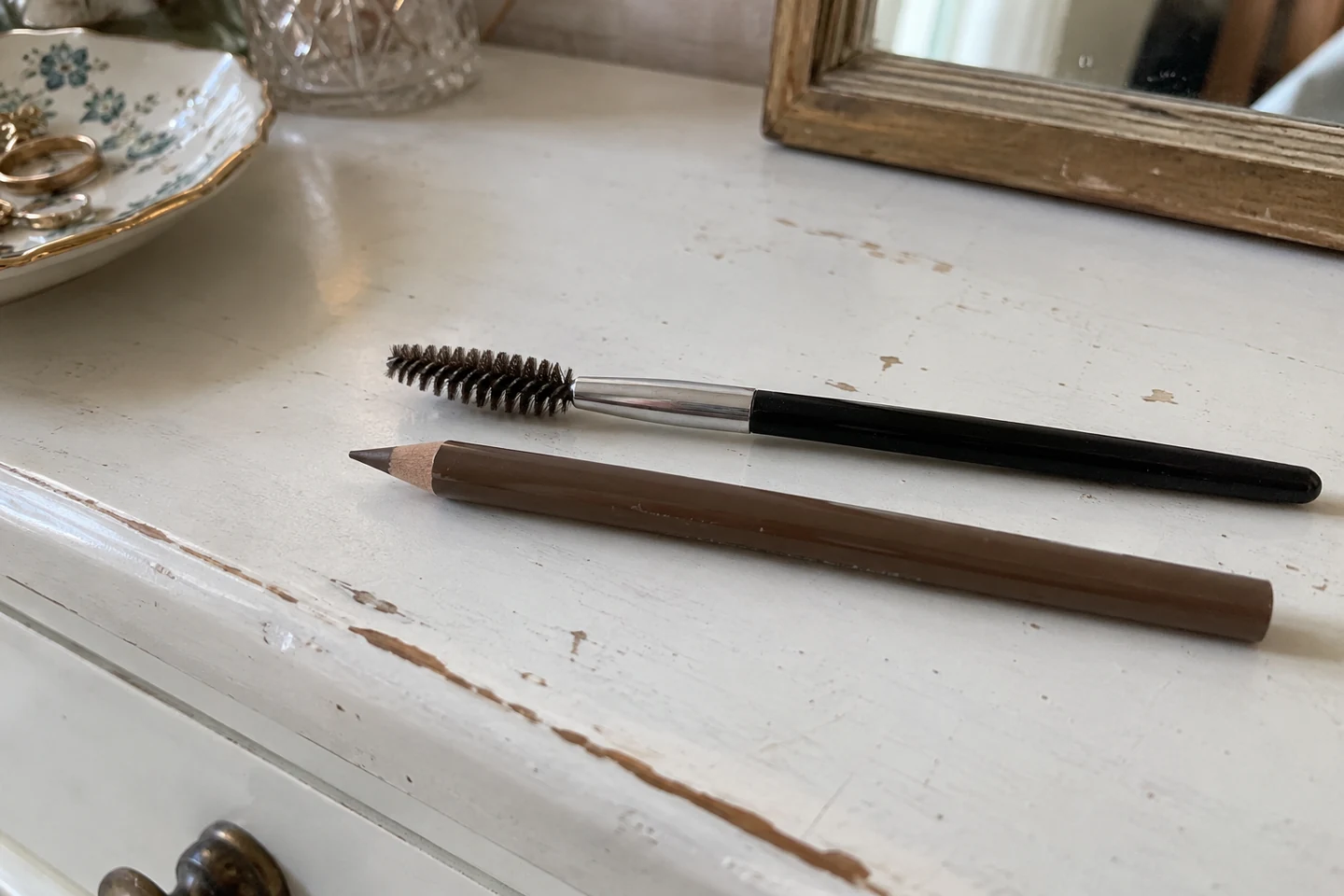 Un crayon brun et un goupillon à sourcils sur une coiffeuse