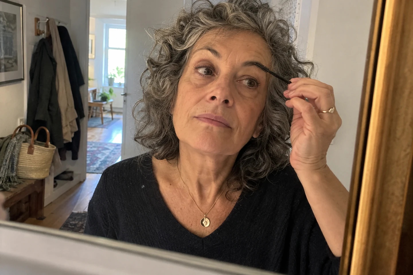 Une femme aux cheveux bouclés se prépare devant un miroir