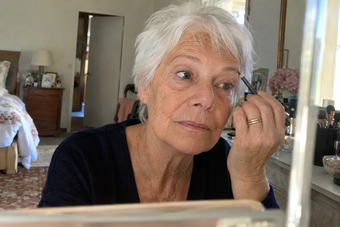 Une femme aux cheveux blancs dessine doucement son sourcil