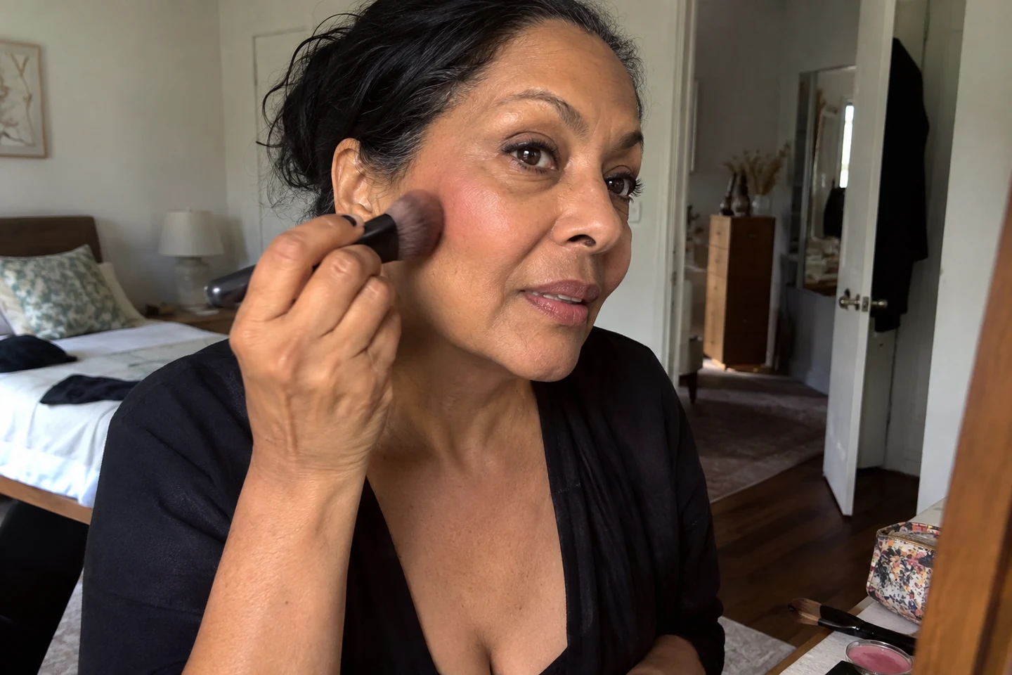 Une femme applique du blush avec un pinceau sur sa joue