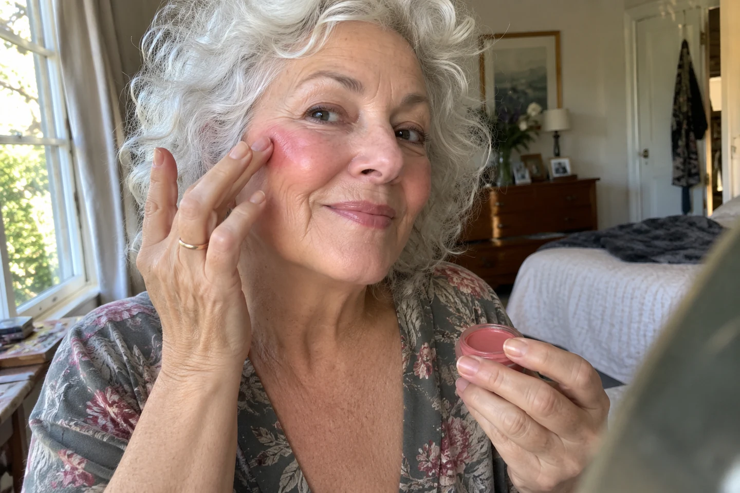 Une femme pose un blush rose avec le bout des doigts