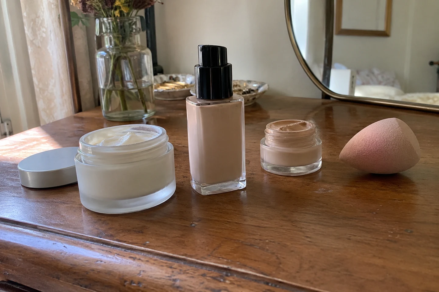 Une crème, un fond de teint et une éponge sur une coiffeuse