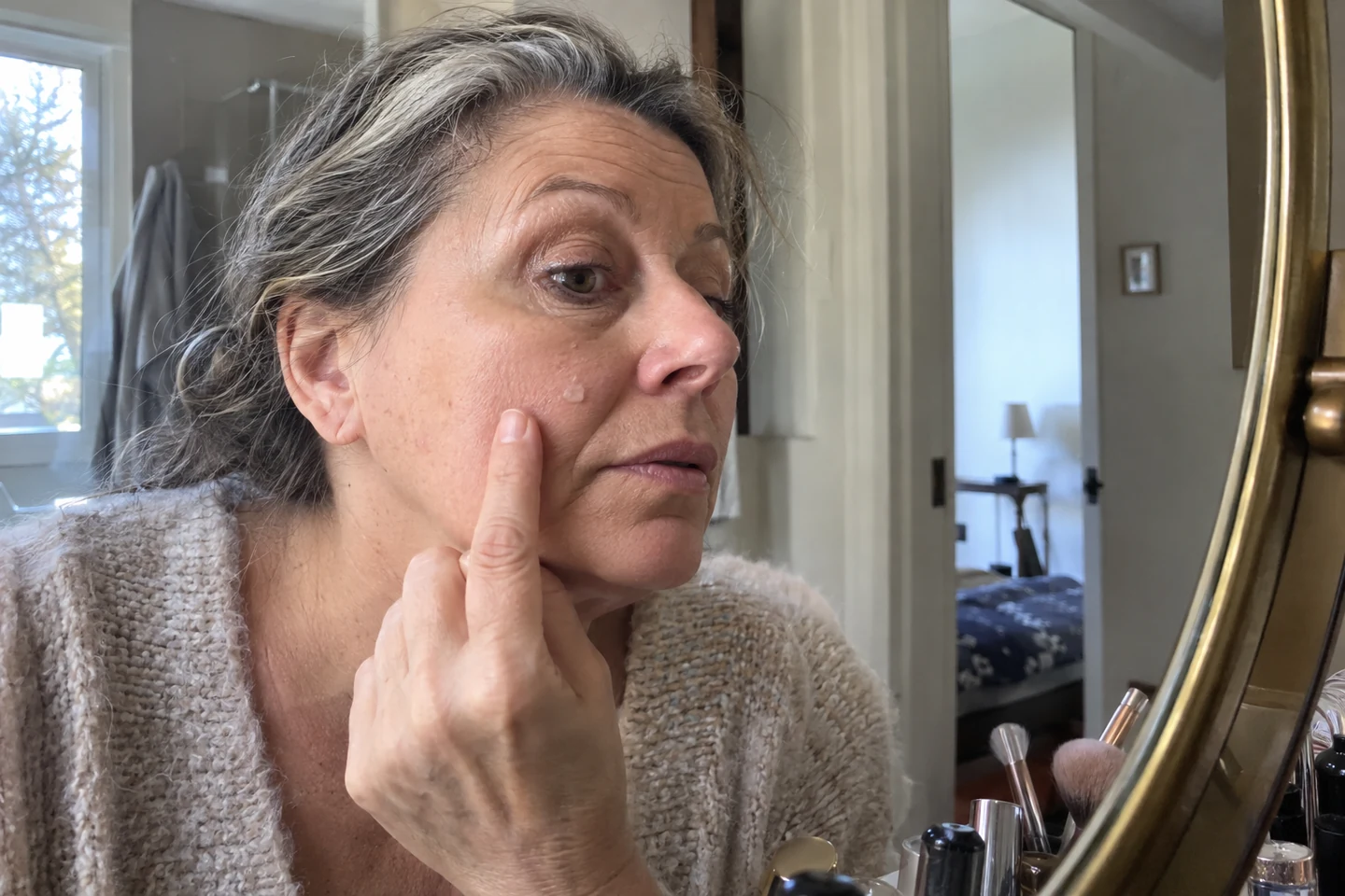 Une femme observe la texture de son maquillage près de la joue
