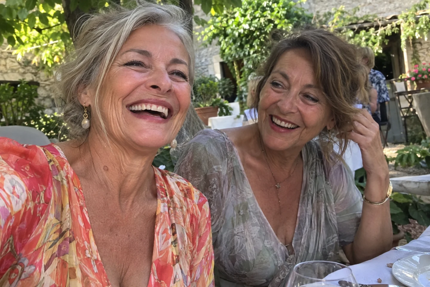 Deux femmes sourient ensemble à une table en plein air