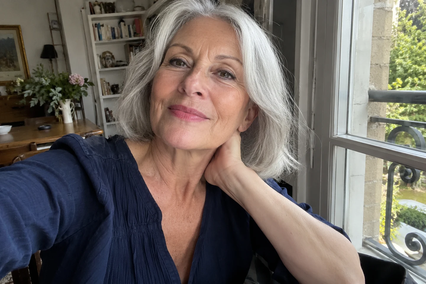 Une femme aux cheveux gris porte un haut bleu et un maquillage léger