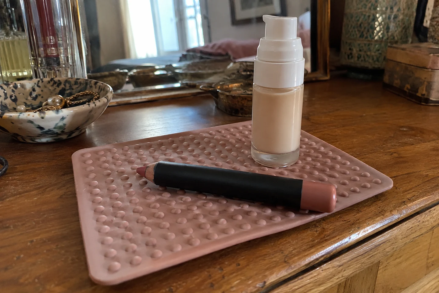 Un flacon pompe et un crayon large posés sur un tapis antidérapant
