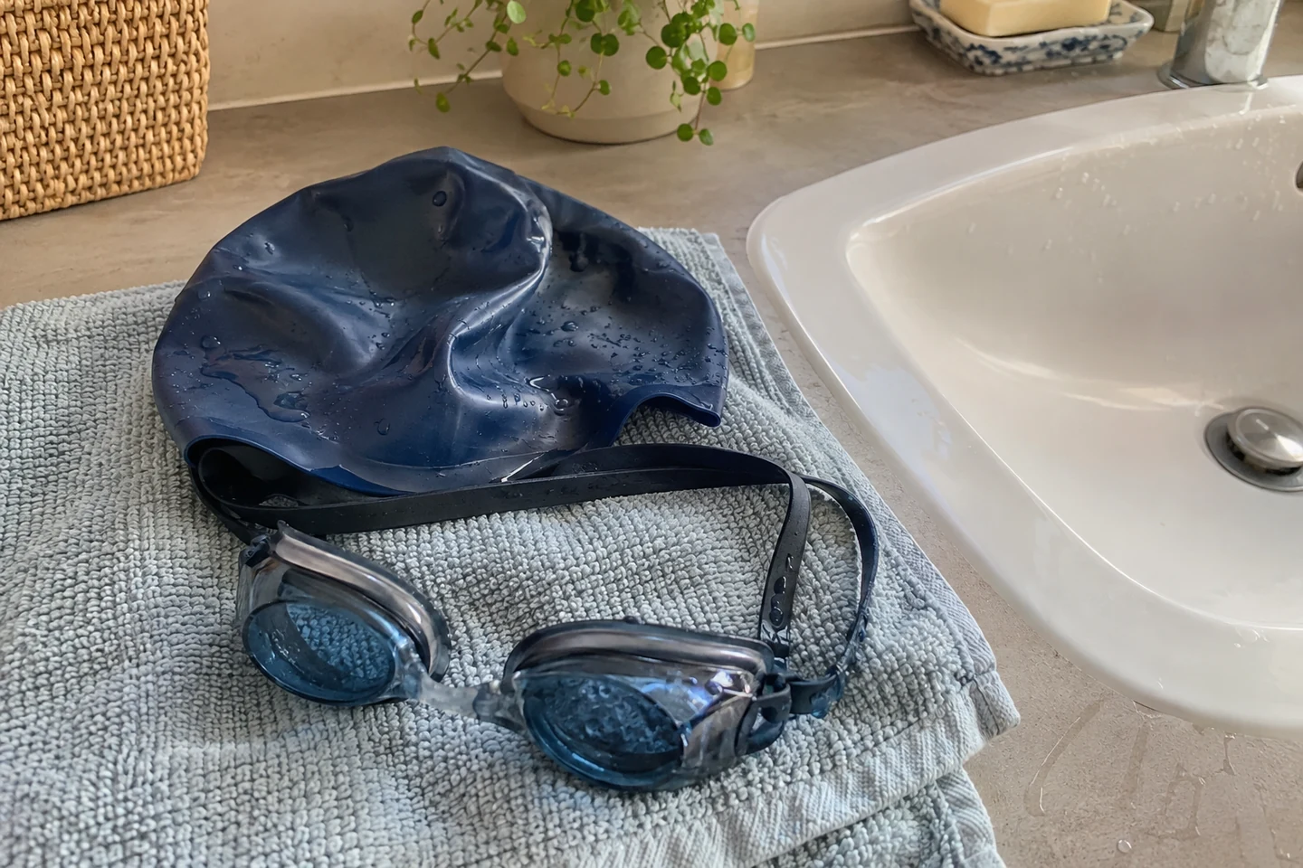 Un bonnet et des lunettes de piscine sèchent sur une serviette près du lavabo