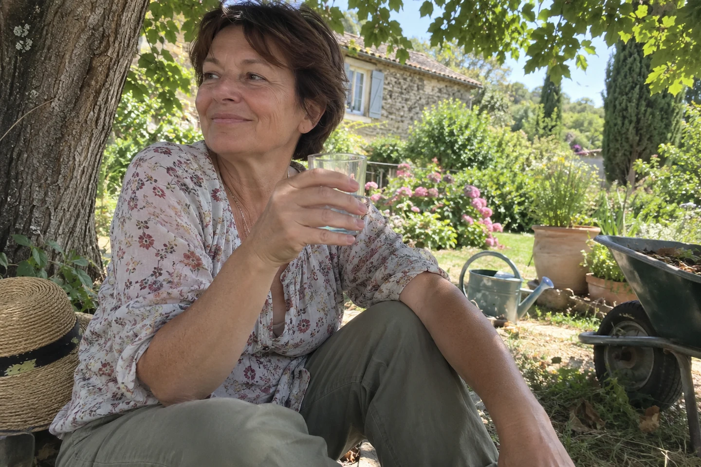 Une femme fait une pause avec un verre d’eau à l’ombre d’un arbre