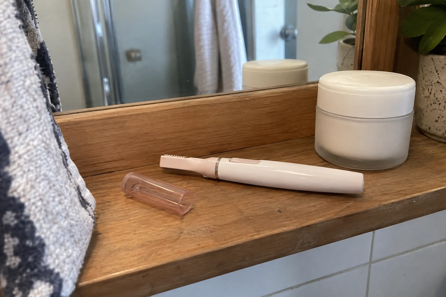 Un petit outil de coupe pour le visage et un pot fermé sur une étagère