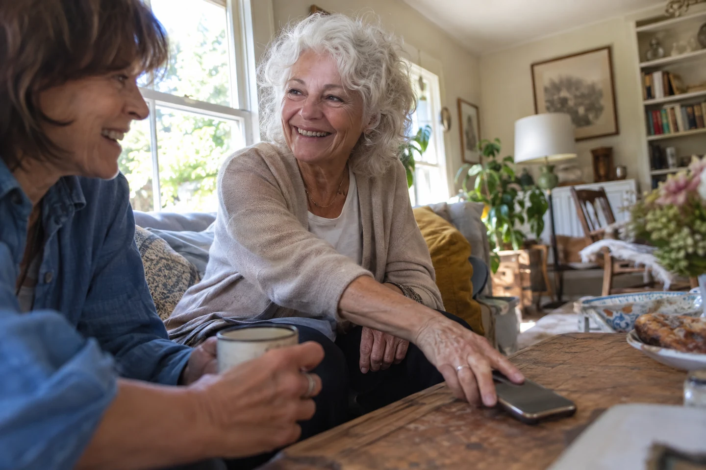 Deux femmes discutent en souriant, leur téléphone posé sur la table