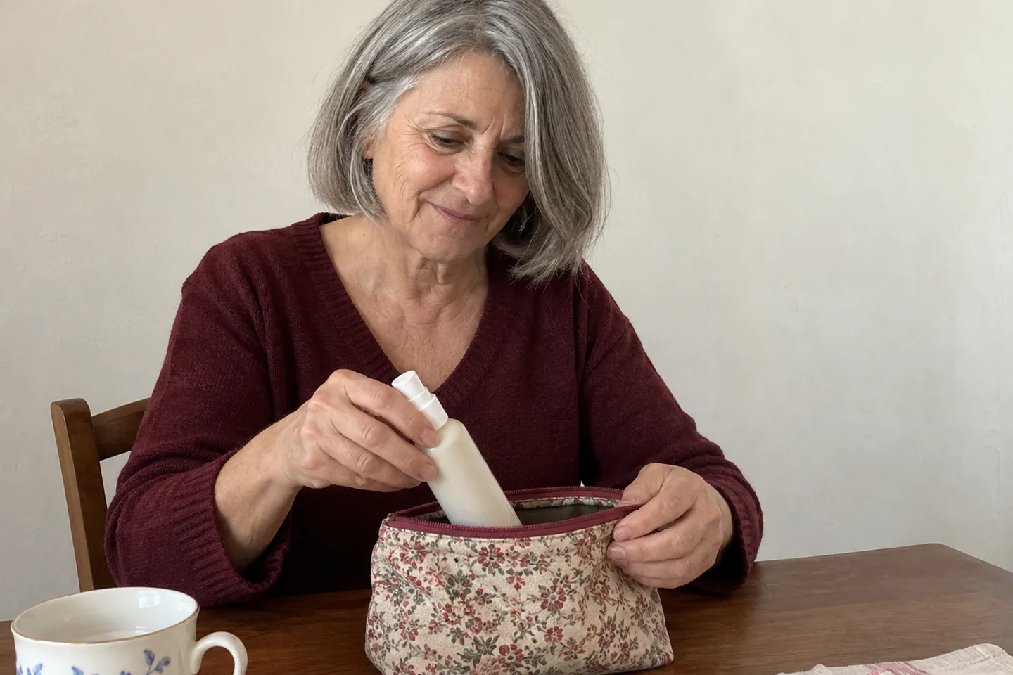 Femme rangeant un flacon de spray dans une petite trousse sur une table