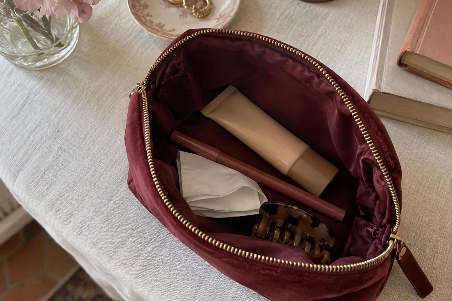 Trousse bordeaux avec un tube fermé, un crayon, un mouchoir et une pince