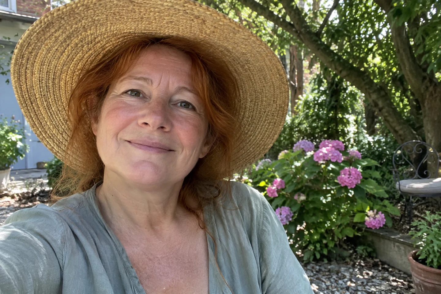 Femme aux joues rosées portant un chapeau dans un jardin ombragé